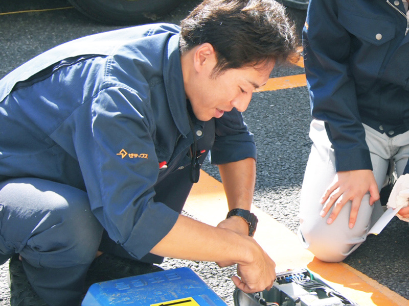 先輩と一緒に駐車場の設備を整備するスタッフ